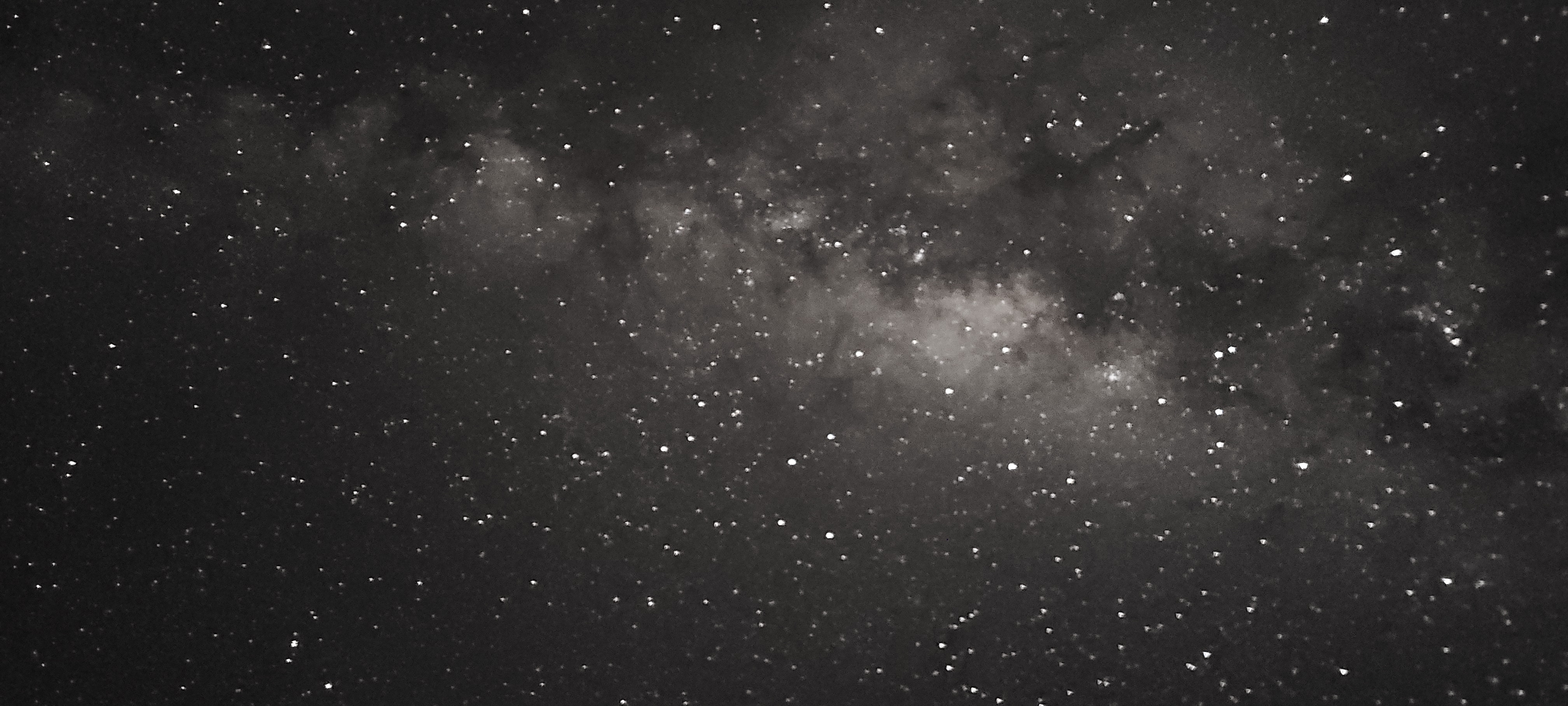A zoom in of a section of the arm of the Milky Way. Bright white stars shine on the backdrop of a dark dust lane.